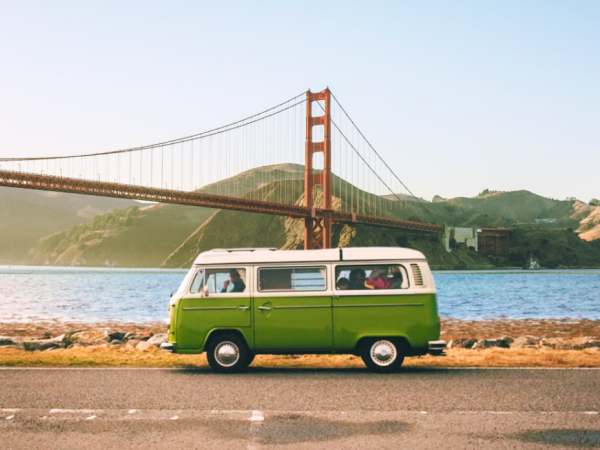 Vintage green VW van parked by the bay with the Golden Gate Bridge behind