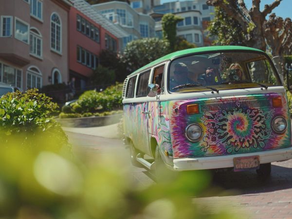 Colorful tie-dye VW van driving through a San Francisco neighborhood