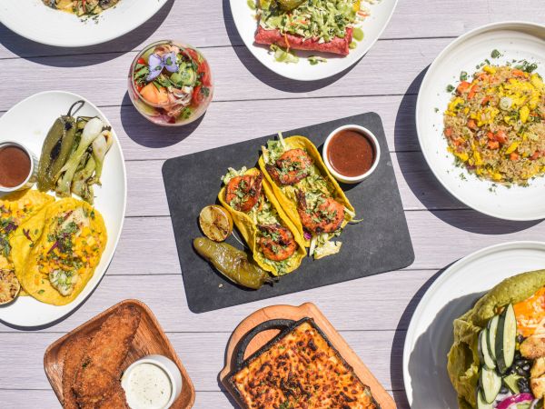 A table spread of colorful meals&mdash;tacos, rice bowls, salad, grilled meats, olives, peppers, and dipping sauces, all served together.