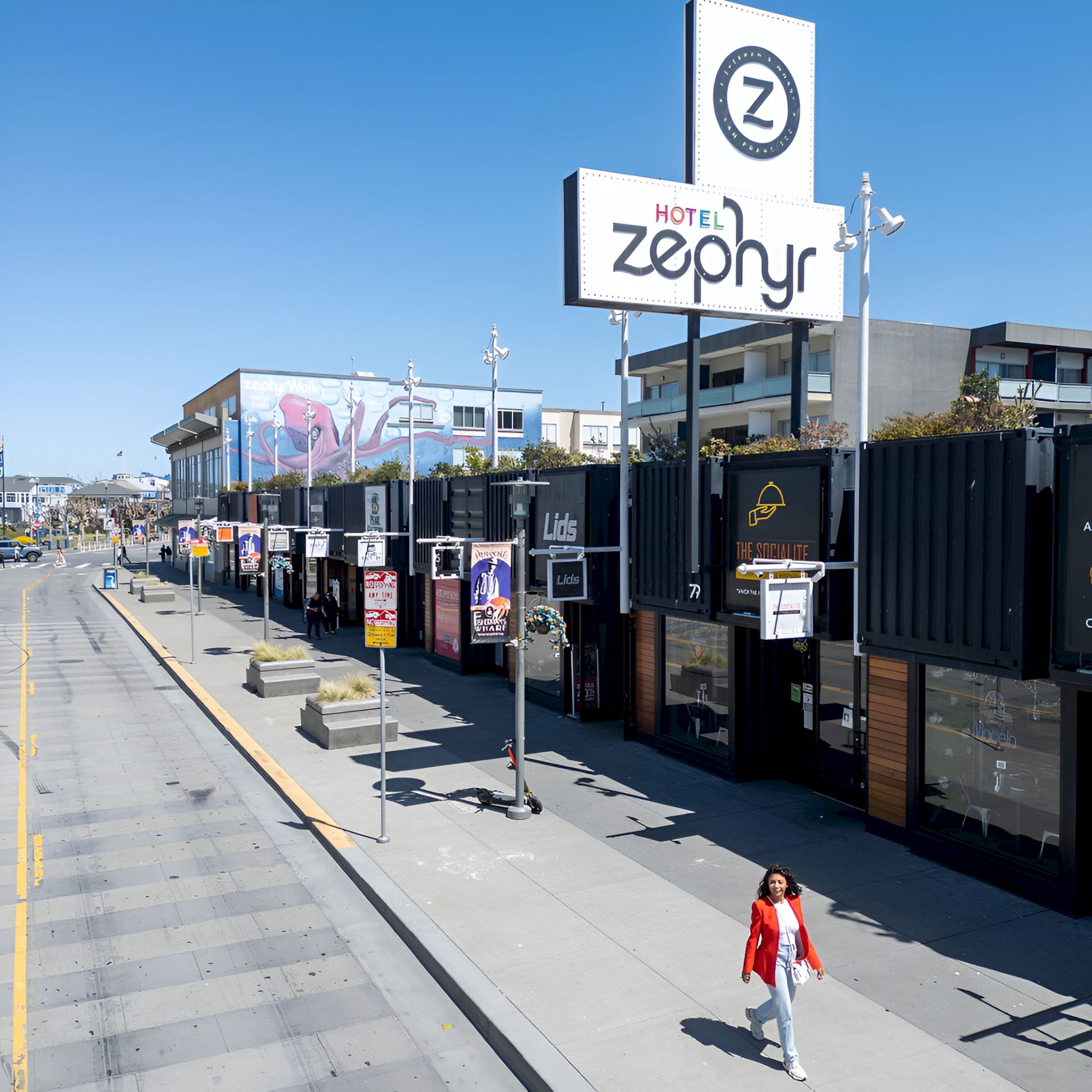 A sunny street scene with an illuminated &ldquo;HOTEL Zepo&rsquo;nyr&rdquo; sign and a big &ldquo;7&rdquo; panel on the building.